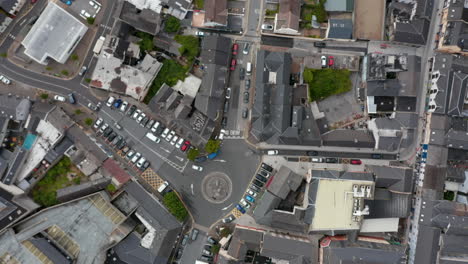 Aerial-birds-eye-overhead-top-down-ascending-view-of-cars-passing-through-roundabout-in-town-centre.-Town-development-from-height.-Ennis,-Ireland