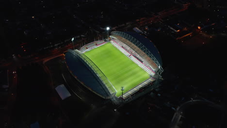 High-angle-view-of-illuminated-empty-football-stadium.-Tilt-up-reveal-night-city-scene.-Limerick,-Ireland