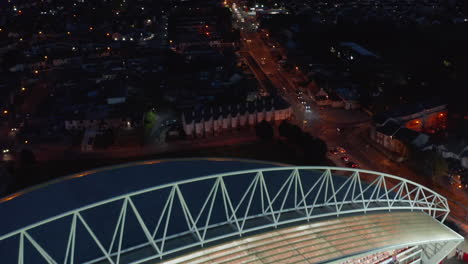 Fly-over-Thomond-Park-Stadium.-Tilt-up-reveal-night-cityscape.-Aerial-view-of-cars-driving-on-street.-Limerick,-Ireland