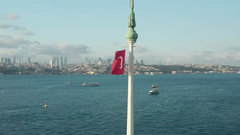 Vibrant-Red-Turkish-Flag-waving-in-wind-on-top-of-Circling-Maiden's-Tower-in-Water-in-Istanbul,-Aerial-circling-shot