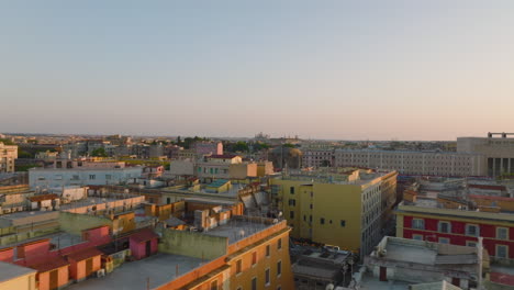 Forwards-fly-above-apartment-buildings-in-urban-borough-at-golden-hour.-Revealing-trains-slowly-moving-on-multitrack-railway-line.-Rome,-Italy