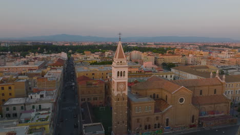 Aerial-ascending-footage-of-church-with-square-tower.-Revealing-urban-boroughs-with-residential-buildings-at-twilight.-Rome,-Italy