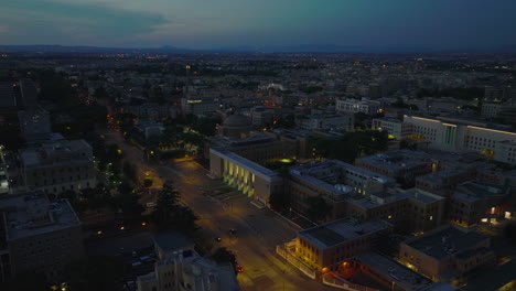 Luftrutsche-Und-Schwenkaufnahmen-Des-Sapienza-Komplexes-Der-Universität-Bei-Nacht.-Beleuchtete-Straßen-Und-Hohes-Eingangstor-Zum-Gelände.-Rom,-Italien