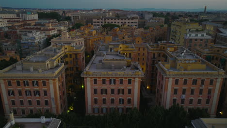 Aerial-ascending-footage-of-group-of-multistorey-apartment-buildings-with-colour-facades.-Residential-urban-borough-at-twilight.-Rome,-Italy