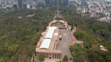 Fly-over-Chapultepec-castle-and-park.-Tilt-up-reveal-of-wide-Avenida-Paseo-de-la-Reforma-street-lined-by-tall-commercial-buildings.-Mexico-City,-Mexico.