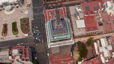 Aerial-high-angle-view-of-tall-building-Torre-Latinoamericana-with-surroundings.-Drone-camera-flying-around-and-rotating.-Mexico-city,-Mexico.