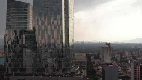 Aufsteigende-Aufnahmen-Eines-Modernen-Bürogebäudes-Aus-Glas.-Dramatischer-Bewölkter-Himmel-Vor-Starkem-Regen.-Mexiko-Stadt,-Mexiko.
