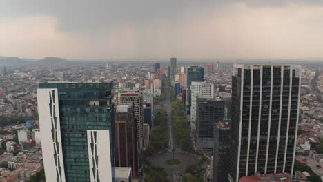 Forwards-reveal-of-wide-long-straight-boulevard-surrounded-by-tall-modern-office-buildings.-Cloudy-sky-before-rain-or-storm.-Mexico-City,-Mexico.