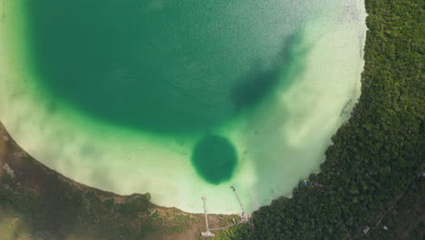 Aerial-birds-eye-overhead-top-down-panning-view-of-extraordinary-natural-landmark.-Emerald-green-water-in-lake.-Kaan-Luum-lagoon,-Tulum,-Yucatan,-Mexico