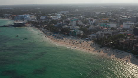Aerial-view-of-sandy-beach-and-holiday-resort-in-Playa-del-Carmen,-Mexico.-Orbit-shot-above-the-Caribbean-Sea-during-sunset
