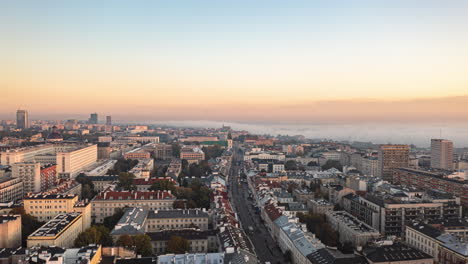 Morning-backwards-fly-above-urban-neighbourhood.-Hyperlapse-of-cityscape-at-sunrise,-mist-rolling-in-background.-Warsaw,-Poland