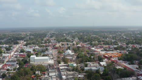 Forwards-fly-above-town.-Aerial-view-of-Iglesia-de-San-Servacio,-Christian-church-and-public-park-in-front.-Valladolid,-Mexico