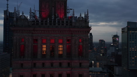Top-part-of-historic-building-with-decorations.-Slide-reveal-of-downtown-skyscrapers-in-twilight-time.-Warsaw,-Poland