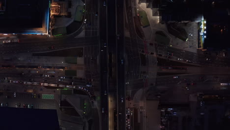 Aerial-birds-eye-overhead-top-down-ascending-footage-of-busy-multilane-and-multilevel-intersection.-Cars-driving-through-night-city.-Warsaw,-Poland