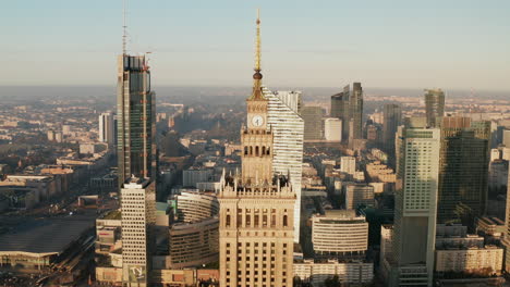 Ascending-shot-of-top-of-historic-high-rise-PKIN-building.-Modern-downtown-skyscrapers-in-background.-Warsaw,-Poland