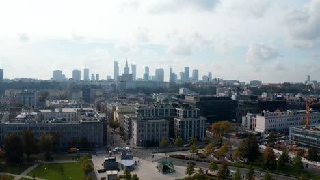 Fly-above-park-in-town-district-with-view-of-modern-high-rise-office-buildings-in-background.-Warsaw,-Poland