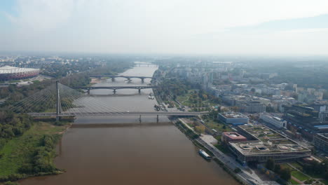 Aerial-view-of-various-bridges-crossing-Vistula-river-in-town.-Modern-National-stadium-on-riverbank.-Warsaw,-Poland