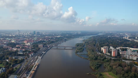 Aerial-panoramic-footage-of-city-around-wide-river.-Heavy-traffic-on-riverbank-roads.-Warsaw,-Poland