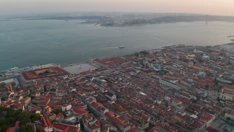Aerial-wide-panoramic-reveal-of-coastal-houses-and-famous-tourist-landmarks-along-the-sea-in-Lisbon-city-center