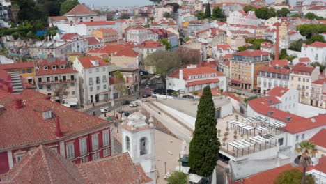 Aerial-view-of-colorful-houses-and-red-rooftops-with-city-traffic-on-the-streets-surrounded-by-traditional-homes-in-busy-urban-city-center-of-Lisbon