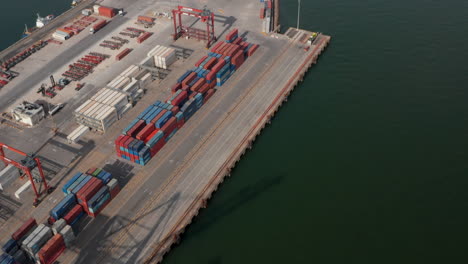 Aerial-view-of-cargo-containers-in-Lisbon-port.-Reveal-of-Lisbon-city-center-on-the-sea-shore-by-industrial-cargo-port