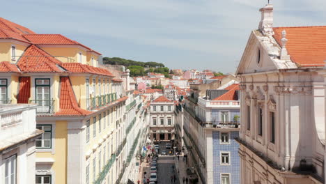 Drone-camera-flying-forwards-over-street-in-level-of-surrounding-buildings-top-floor.-Aerial-view-of-Rua-Garrett,-principal-shopping-street-in-Chiado.-Lisbon,-capital-of-Portugal.