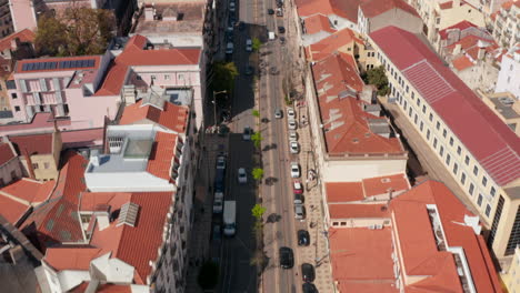 Aerial-dolly-in-reveal-of-multi-lane-road-traffic-through-Lisbon-city-center-surrounded-by-traditional-colorful-houses