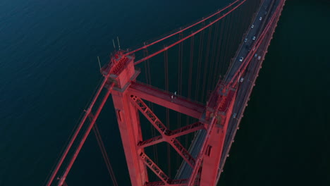 Drohne-Fliegt-über-Brückenpfeiler-Und-Kamera-Kippt-Nach-Unten.-Große-Rote-Mehrspurige-Autobahnbrücke-über-Den-Fluss.-Lissabon,-Hauptstadt-Von-Portugal.