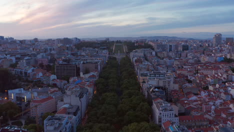 Aerial-slow-dolly-in-view-of-large-public-park-Parque-Eduardo-VII-with-lush-green-vegetation-in-urban-city-center-of-Lisbon,-Portugal