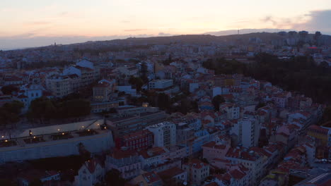 Aerial-view-of-evening-town-against-bright-sunset-sky.-Drone-flying-along-streets.-Lisbon,-capital-of-Portugal.