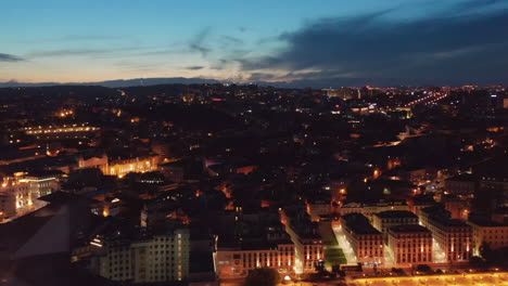Nachtflug-über-Die-Burg-Von-Lissabon-In-Richtung-Eines-Großen-öffentlichen-Platzes,-Der-Von-Modernen-Gebäuden-Im-Stadtzentrum-Umgeben-Ist