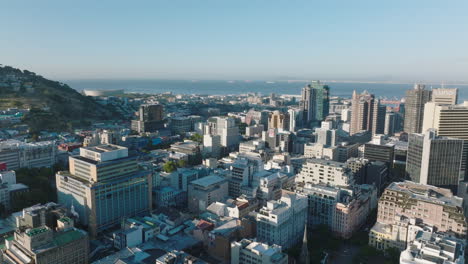 Aerial-ascending-footage-of-high-rise-office-buildings-in-city-centre.-Sea-bay-with-seaport-in-background.-Cape-Town,-South-Africa