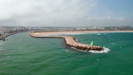Luftaufnahme-Der-Wellenbrecherstruktur-An-Der-Küste-Von-Lagos,-Algarve,-Portugal,-Drohne-Kreist-über-Windigem-Meer,-Tag