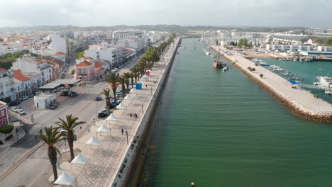 Aerial-drone-view-of-picturesque-city-of-Lagos-Algarve,-Portugal,-drone-flying-forward-above-harbor-canal,-day