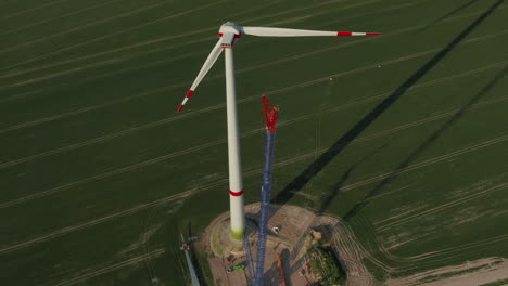 Fly-over-construction-site-of-new-wind-turbine.-Propeller-with-big-diameter-high-above-green-field.-Green-energy,-ecology-and-carbon-footprint-reduction-concept
