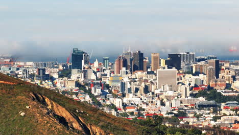 Aerial-panoramic-view-of-modern-city-borough-gradually-hiding-behind-grassy-slope-of-hill.-Cape-Town,-South-Africa