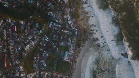 Aerial-birds-eye-overhead-top-down-view-of-rough-sea-waves-rolling-on-coast-in-city.-Cape-Town,-South-Africa