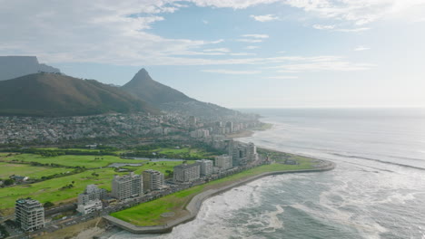 Aerial-panoramic-footage-of-sea-coast.-Multistorey-hotel-or-apartment-buildings-and-bright-green-lawn-around.-Cape-Town,-South-Africa