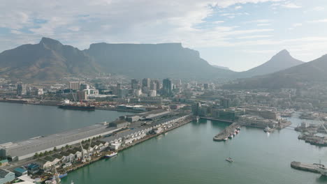 Forwards-fly-above-Victoria-and-Alfred-Waterfront-and-Table-Bay-Harbour.-Cityscape-and-flat-topped-Table-Mountain-massif.-Cape-Town,-South-Africa