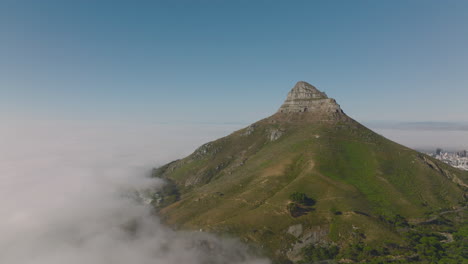 Montaña-De-Cabeza-De-León-Saliendo-De-La-Niebla.-Toma-Aérea-Descendente-De-Pendientes-Pronunciadas-Y-Pico-Rocoso.-Ciudad-Del-Cabo,-Sudáfrica