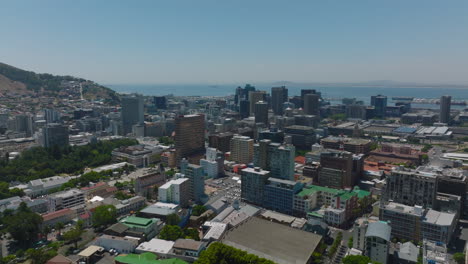 Slide-and-pan-aerial-shot-of-multistorey-office-of-apartment-buildings-in-town.-Sea-in-background.-Cape-Town,-South-Africa