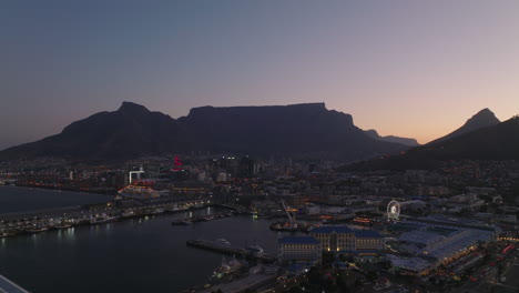 Harbour-and-entertaining-urban-borough-at-waterfront-in-evening.-Forwards-fly-above-sea-coast-at-dusk.-Cape-Town,-South-Africa