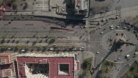 Birds-eye-shot-of-traffic-in-streets-around-Columbus-Monument.-Vehicles-driving-on-road-and-roundabout.-Palm-trees-casting-shadows-on-asphalt-surface.-Barcelona,-Spain