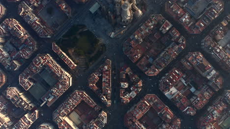 Top-down-shot-of-town-development-at-golden-hour.-Revealing-basilica-Sagrada-Familia.-Barcelona,-Spain
