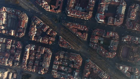 Top-down-rotating-footage-of-blocks-of-buildings-and-streets-in-urban-borough-at-golden-hour.-Barcelona,-Spain