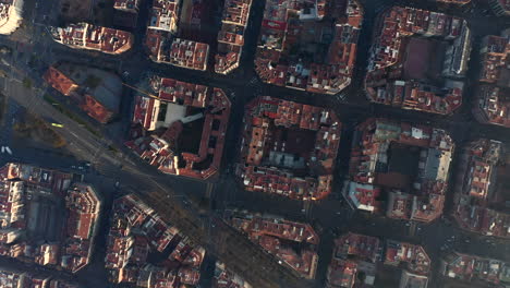 Overhead-shot-of-buildings-arranged-in-square-blocks-and-lined-by-streets.-Fly-above-urban-borough-in-large-city.-Barcelona,-Spain
