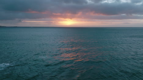 Romantic-aerial-footage-of-surfacing-whale-on-open-sea.-View-against-colourful-sunset-sky.
