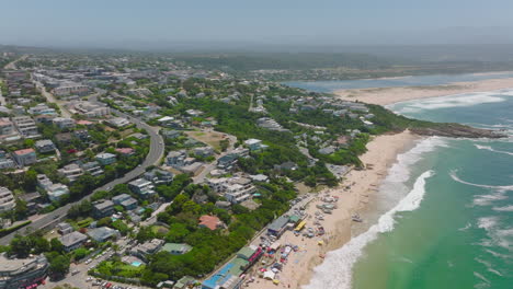 Aerial-panoramic-view-of-town-on-sea-coast-in-tropical-vacation-destination.-Waves-washing-sand-beaches.-Plettenberg-Bay,-South-Africa