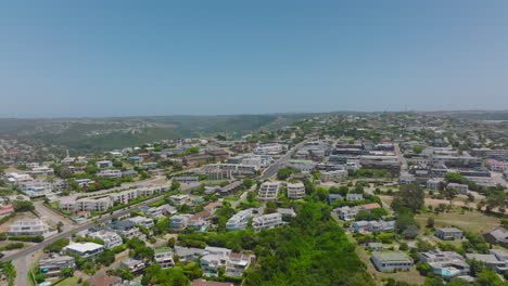 Forwards-fly-above-modern-residential-urban-borough.-Apartment-houses-and-residencies-surrounded-by-rich-green-vegetation.-Plettenberg-Bay,-South-Africa
