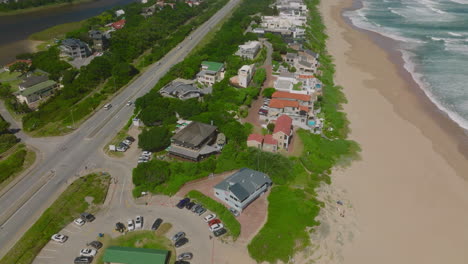 High-angle-view-of-road-and-buildings-at-sand-beach.-Tilt-up-reveal-of-row-of-vacation-houses-along-sea-coast.-South-Africa
